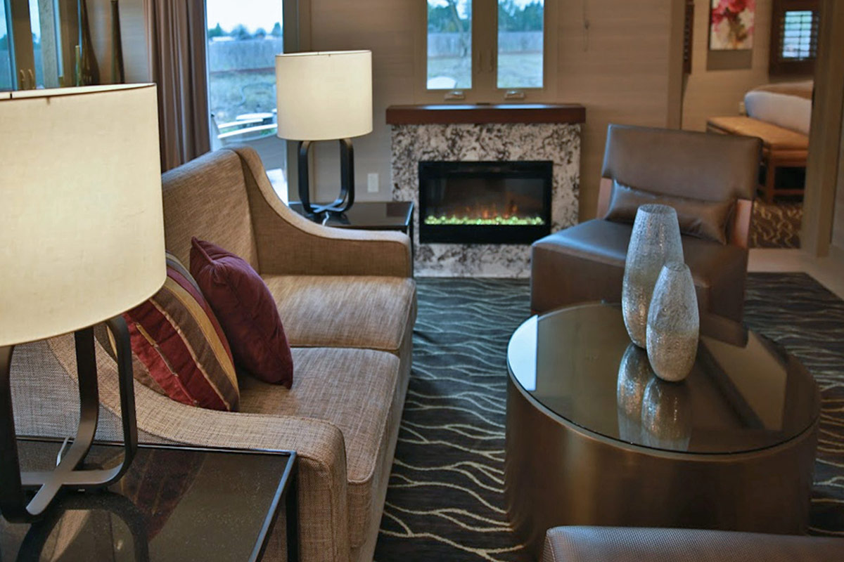The spacious living room of the Vineyard Terrace Deluxe Suite featuring a fireplace and opens to a terrace.