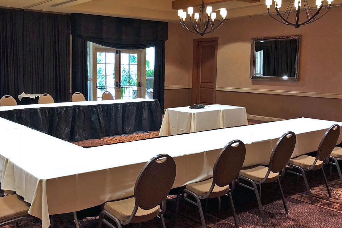 A U-shape conference table set up in the Cypress Room at Vintners Resort, and doors open to the terrace.