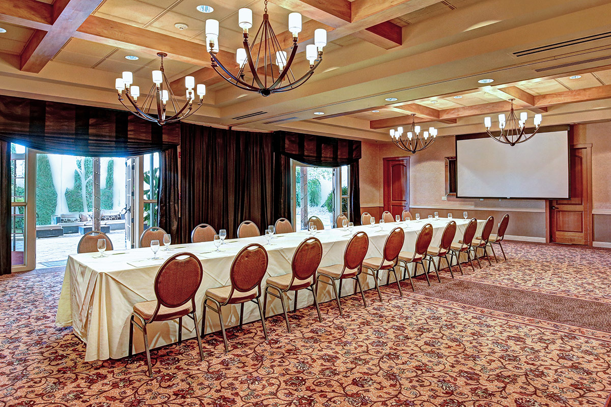 A conference table and chairs set up in the Camelia Room at Vintners Resort. Door opens to the Cypress Room Terrace.