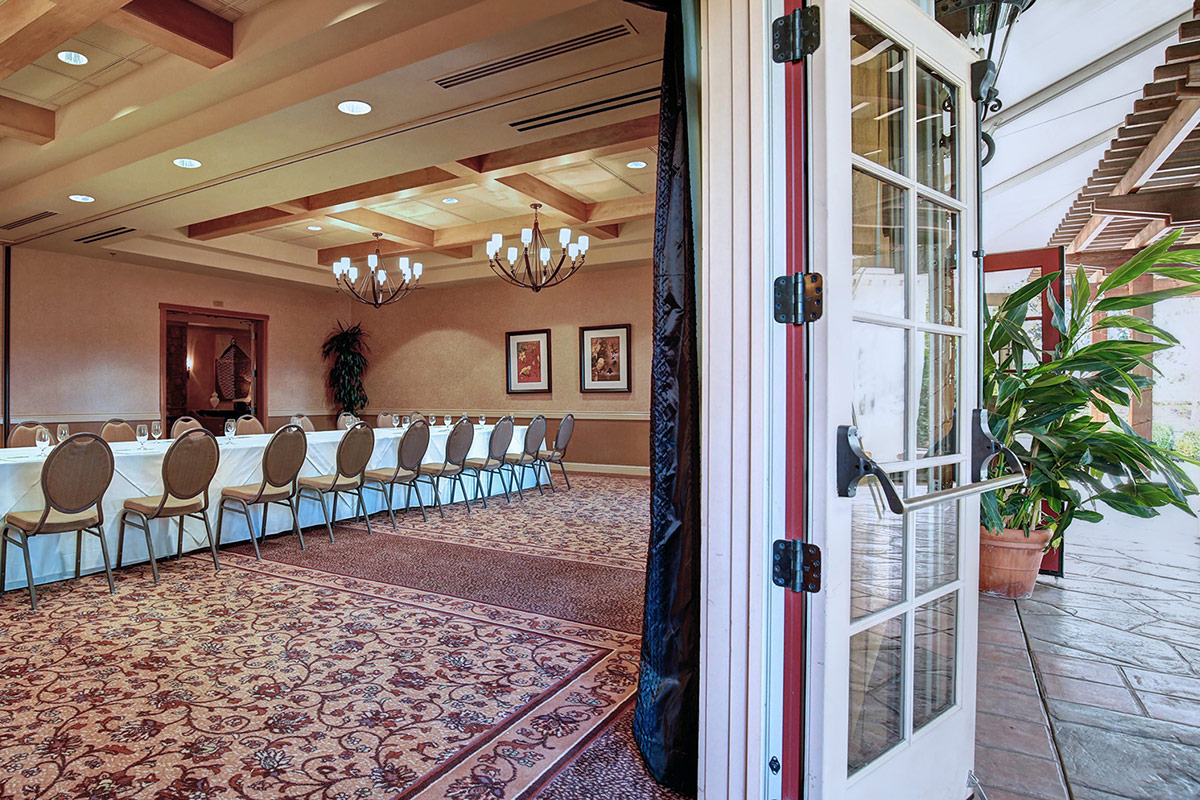 A conference table and chairs set up in the Cypress Room. Door opens to the terrace.