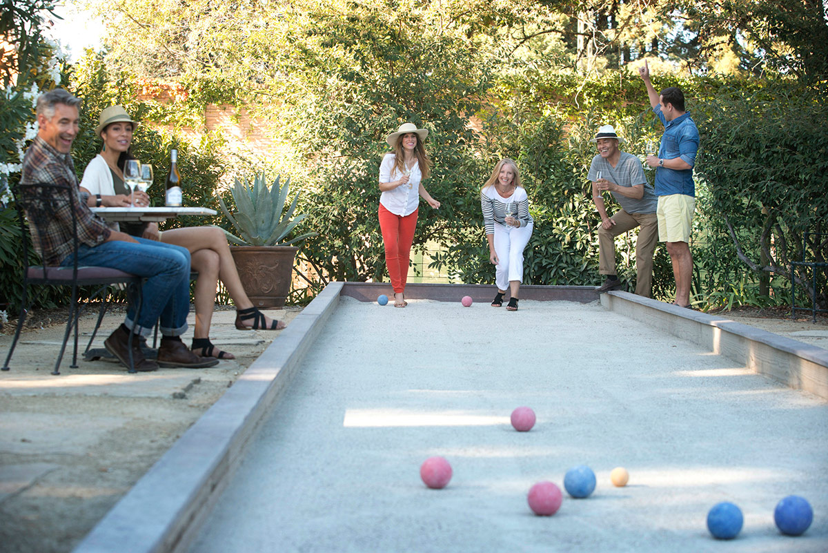 Guests playing at the bocce ball court at Vintners Resort, and spectators enjoying a glass of wine while viewing the game.