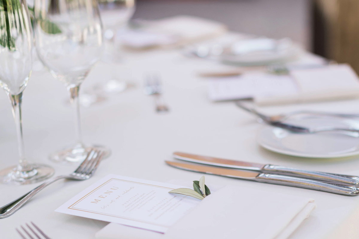 Closeup of a table setting with white linens and silver cutlery in an indoor event space at Vintners Resort.