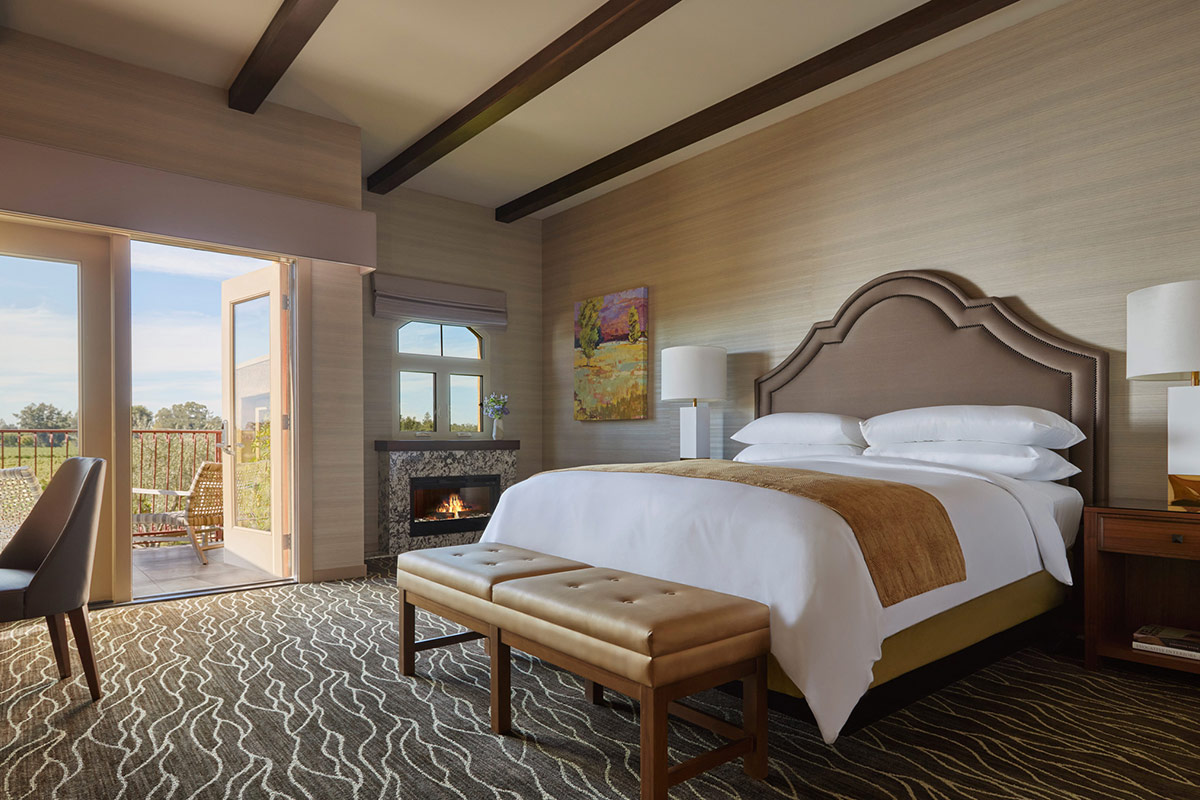 Vineyard View Fireplace King Room at Vintners Resort features a California king feather bed with plush down bedding, a fireplace, and a door opens to a furnished patio or balcony.