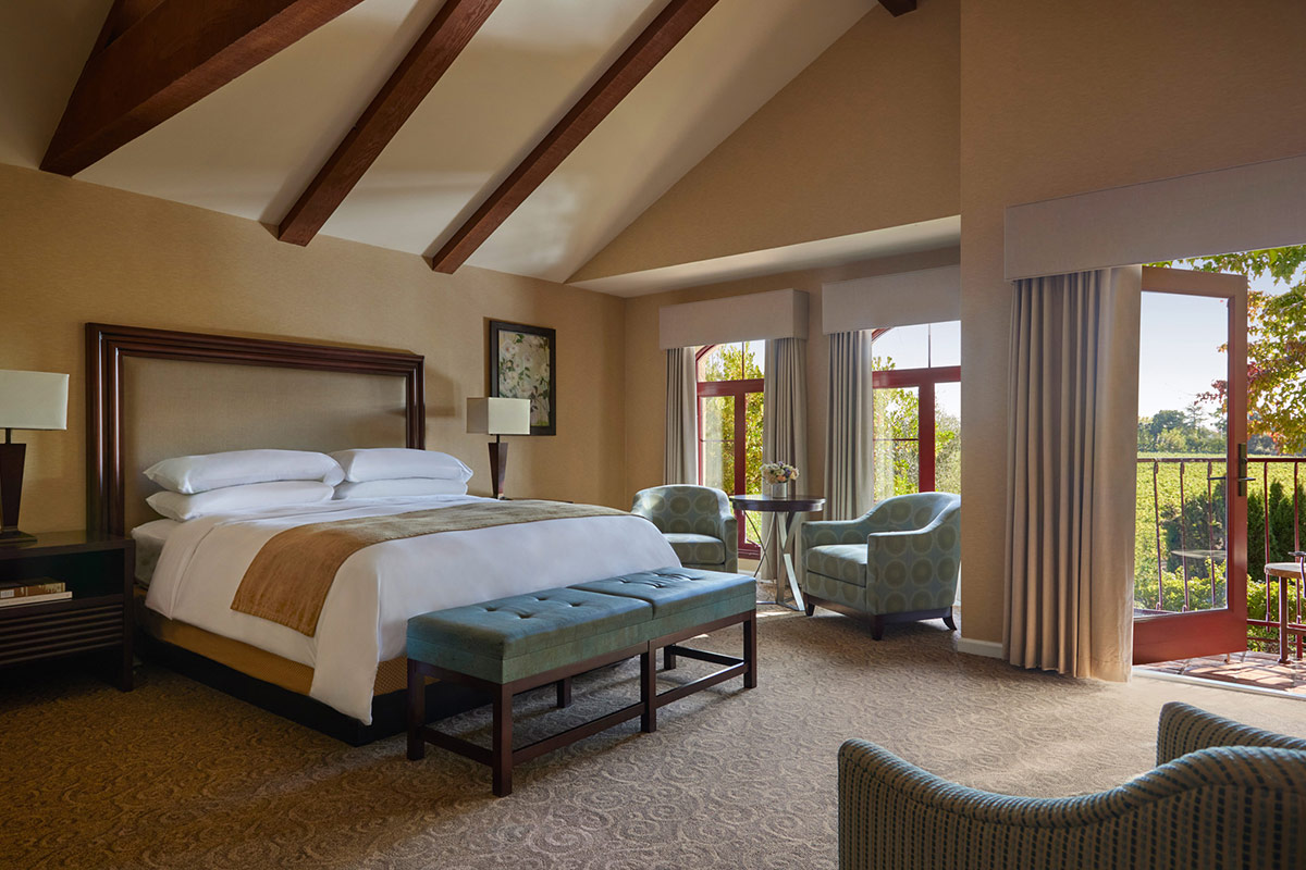 The open-concept Coutryard Junior Suite combines the bedroom with a sitting area. Double French doors lead to a furnished balcony overlooking garden courtyards of Vintners Resort.