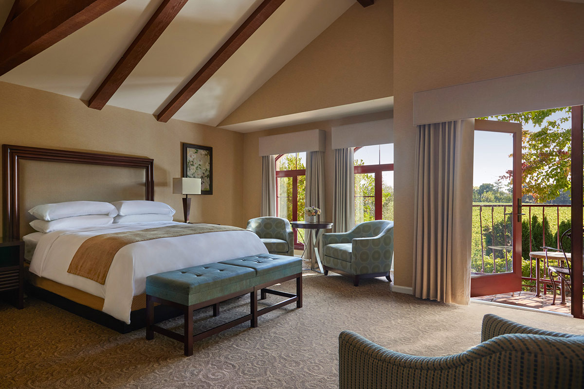 The open-concept Coutryard Junior Suite combines the bedroom with a sitting area. Double French doors lead to a furnished balcony overlooking garden courtyards of Vintners Resort.