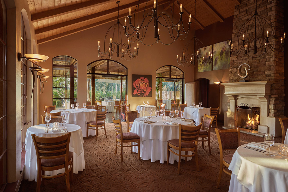 John Ash & Co. main dining room with tables set ready for dinner service, and doors open to the outdoor terrace for al fresco dining, overlooking the vineyard.
