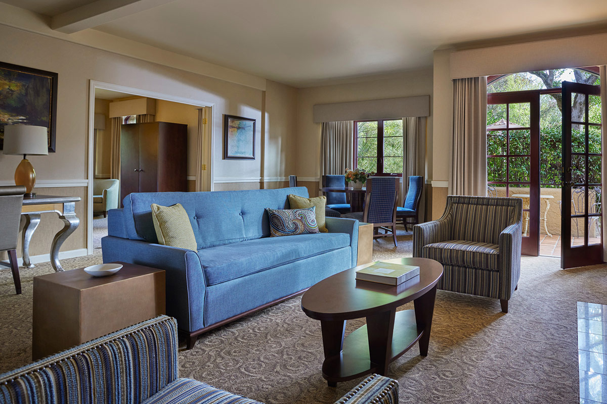 The spacious living and dining room of the Courtyard Suite at Vintners Resort, featues a fireplace and dining table for four. French doors open to a large enclosed patio.